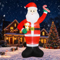 Giant Santa inflatable raising a candy cane and holding a small gingerbread man in a snowy yard