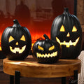 Three black jack-o'-lanterns glowing yellow on a wooden table