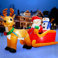 Santa and a snowman in a red sleigh pulled by a reindeer inflatable in the snow