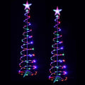 Two multicolor LED spiral Christmas trees with star toppers glowing at night