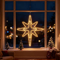 Warm white LED Bethlehem star hanging in a large window at night