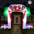 Giant clown face archway inflatable with a toothy mouth and clawed hands over a front path at night
