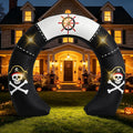 Black pirate arch inflatable with skulls in pirate hats and a ship's wheel over a front walk at night