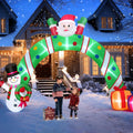Green and red striped Christmas arch inflatable with Santa on top, a snowman and gifts, a family walking through