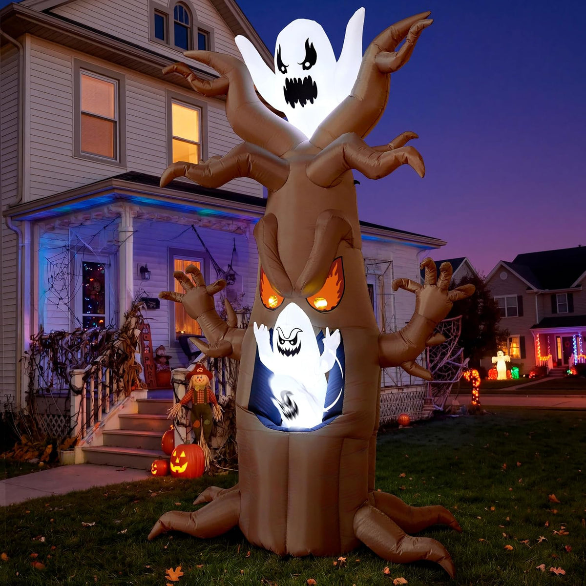 Brown haunted tree inflatable with glowing orange eyes and ghosts on top and in the trunk