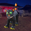 Giant black cat inflatable with an arched back, green eyes and sharp teeth at night